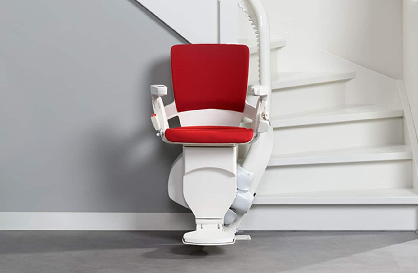 Otolift-traplift met rode zitting op een gebogen trap